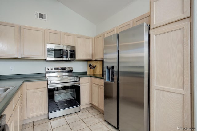 kitchen with visible vents, lofted ceiling, light tile patterned flooring, light brown cabinets, and appliances with stainless steel finishes