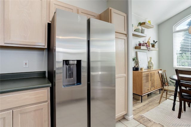kitchen featuring light brown cabinetry, dark countertops, and stainless steel fridge with ice dispenser