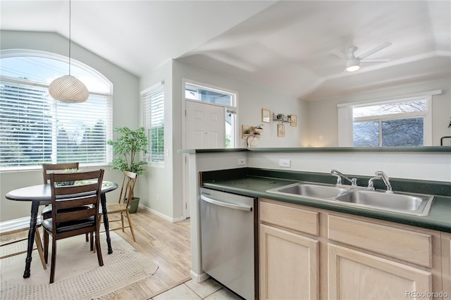 kitchen with lofted ceiling, light brown cabinets, dark countertops, a sink, and dishwasher