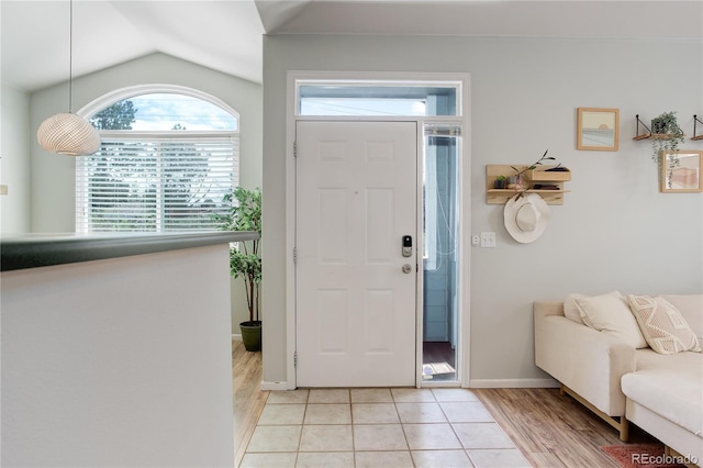 foyer featuring baseboards, light wood-style flooring, and lofted ceiling