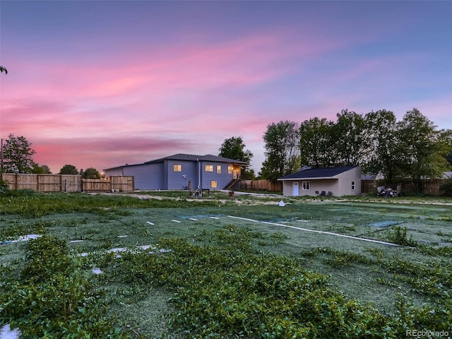 yard at dusk with an outbuilding and fence