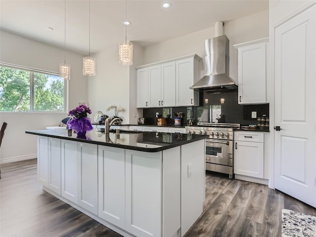 kitchen with high end range, wall chimney range hood, dark countertops, and tasteful backsplash