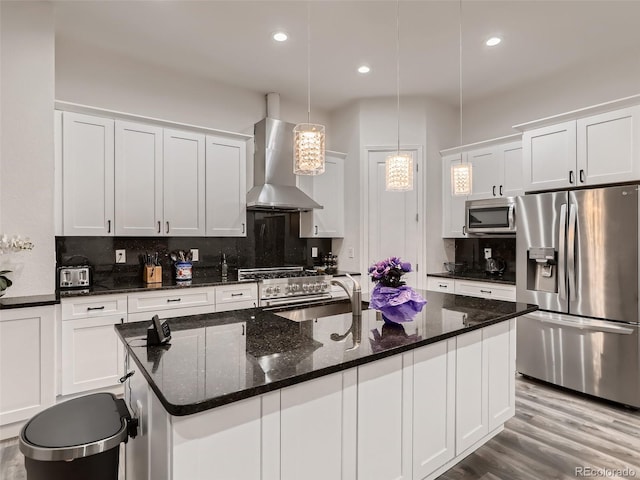 kitchen with a sink, stainless steel appliances, tasteful backsplash, and wall chimney range hood