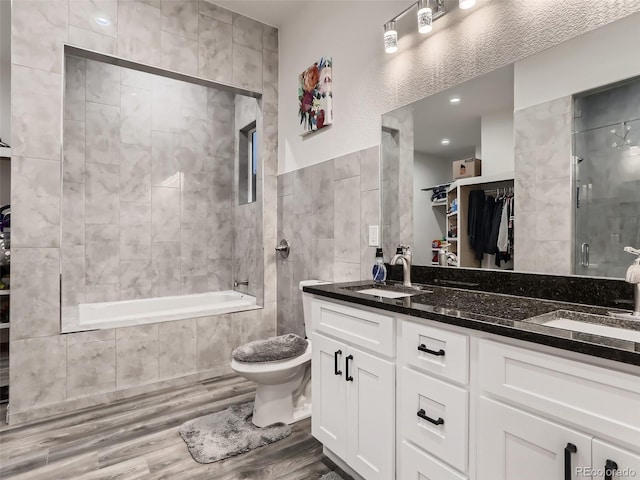 bathroom with double vanity, wood finished floors, tile walls, and a sink