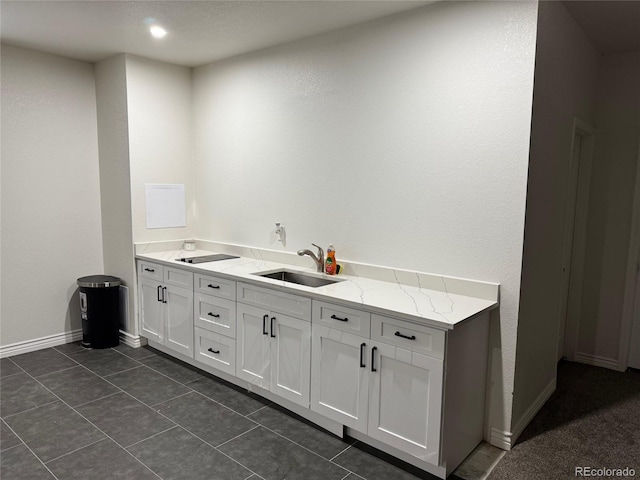 laundry area with dark tile patterned flooring, baseboards, and a sink