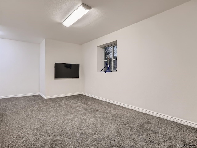 spare room with baseboards and dark carpet