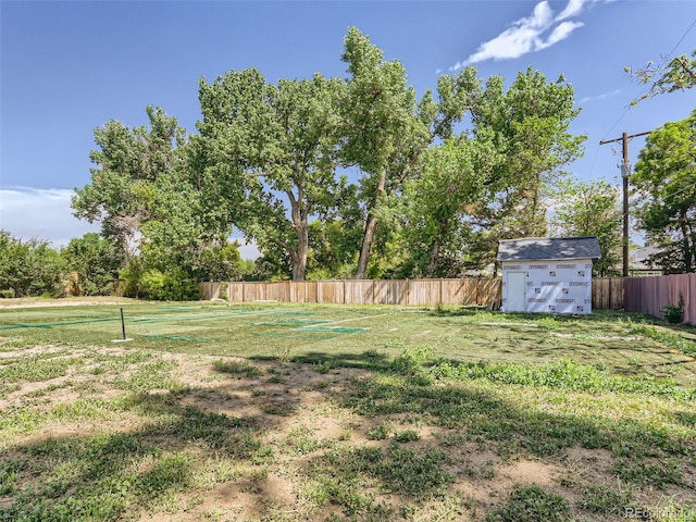 view of yard featuring a storage shed, an outdoor structure, and fence