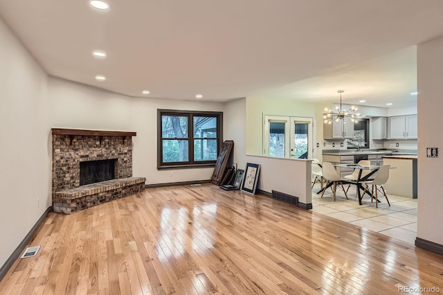 living room with a chandelier, recessed lighting, light wood-type flooring, baseboards, and a fireplace