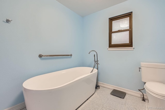 bathroom with a freestanding bath, toilet, and baseboards
