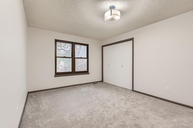 unfurnished bedroom featuring carpet floors, a textured ceiling, a closet, and baseboards