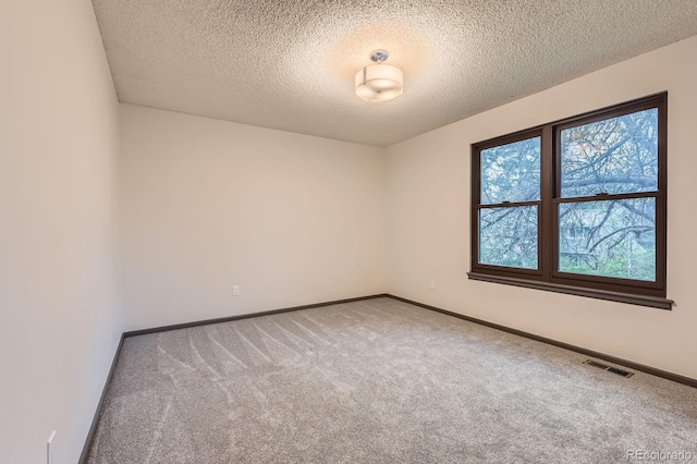 carpeted empty room featuring baseboards and a textured ceiling