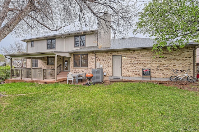 rear view of property featuring central air condition unit, a lawn, brick siding, a chimney, and covered porch