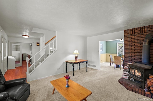 carpeted living room with a textured ceiling and a wood stove