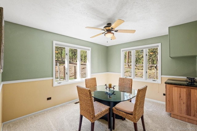 dining space featuring a textured ceiling, ceiling fan, light colored carpet, and a wealth of natural light