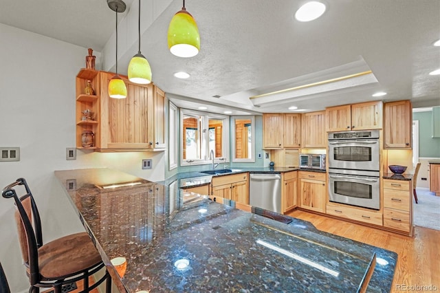 kitchen featuring sink, kitchen peninsula, light hardwood / wood-style floors, stainless steel appliances, and pendant lighting