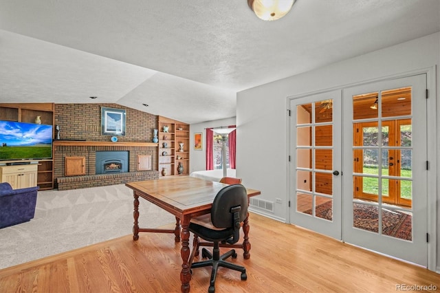 office space with lofted ceiling, french doors, built in features, a textured ceiling, and light hardwood / wood-style floors