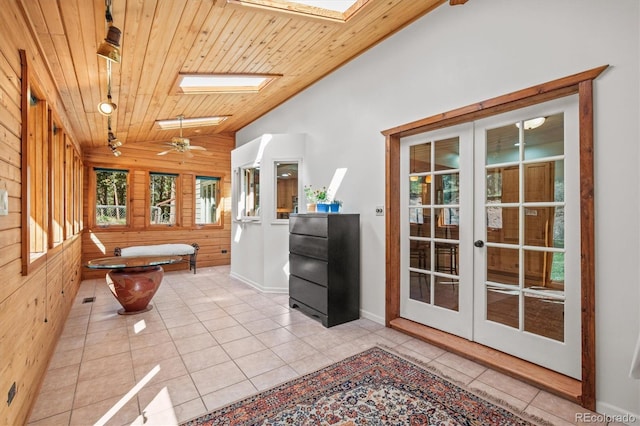 bathroom with wood walls, tile patterned floors, wood ceiling, vaulted ceiling with skylight, and ceiling fan