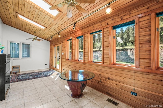 interior space featuring lofted ceiling with skylight, wooden walls, wood ceiling, and a healthy amount of sunlight