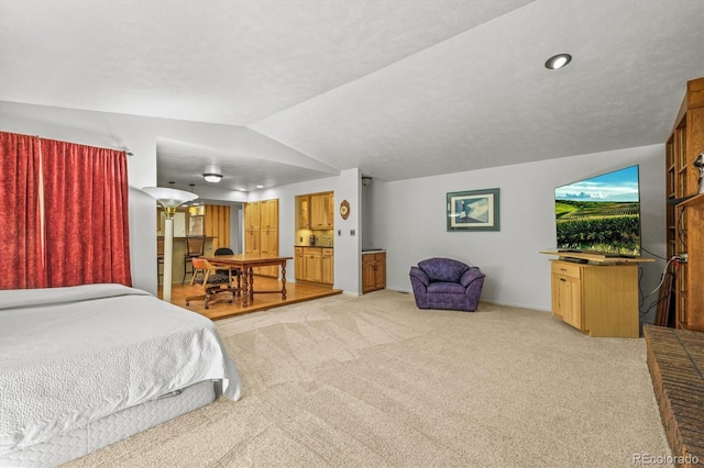 carpeted bedroom with vaulted ceiling and ensuite bathroom