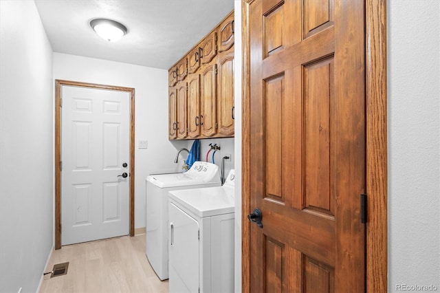 laundry room featuring light hardwood / wood-style flooring, cabinets, and washer and clothes dryer