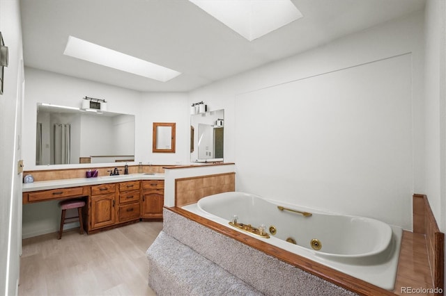 bathroom with vanity, a skylight, hardwood / wood-style flooring, and a bath