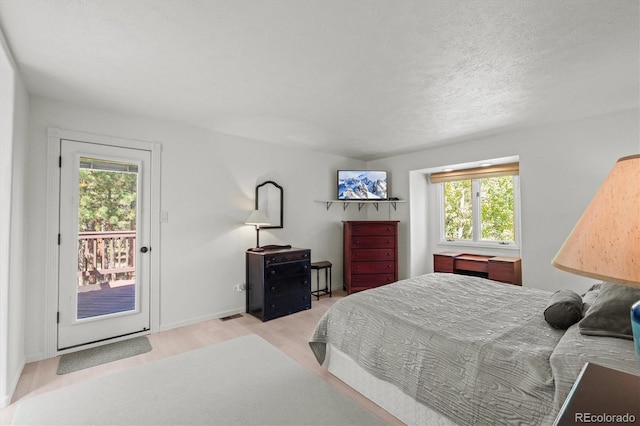 bedroom featuring a textured ceiling, multiple windows, access to exterior, and light hardwood / wood-style floors