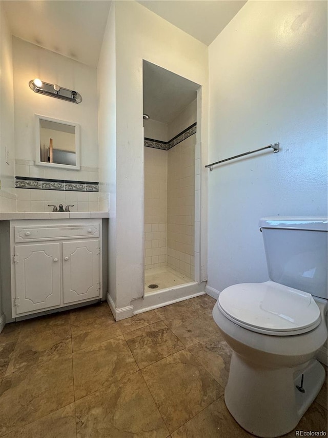 bathroom featuring a tile shower, backsplash, vanity, and toilet