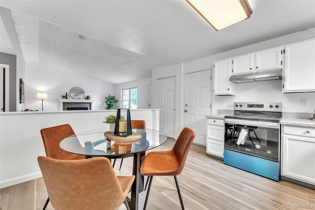 8479 Rabbitbrush Way, Parker, CO 80134 - kitchen with electric range, under cabinet range hood, white cabinetry, light wood finished floors, and lofted ceiling