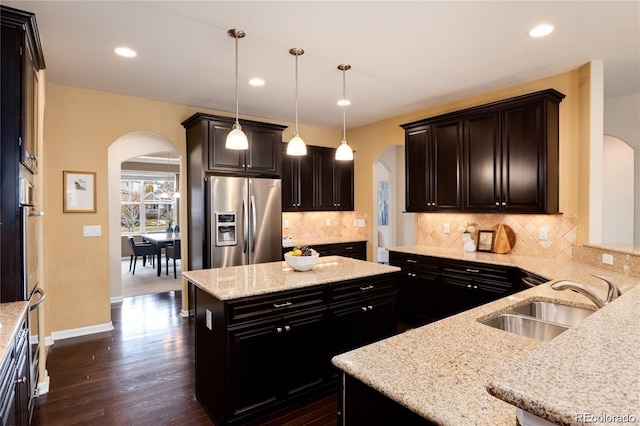 27235 E Lakeview Pl, Aurora, CO 80016 - kitchen with arched walkways, appliances with stainless steel finishes, light stone counters, dark wood-style floors, and a center island