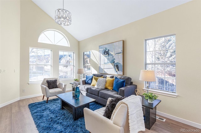 living room featuring high vaulted ceiling, hardwood / wood-style floors, and a chandelier