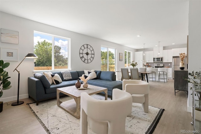 living area with baseboards, recessed lighting, and light wood-style floors