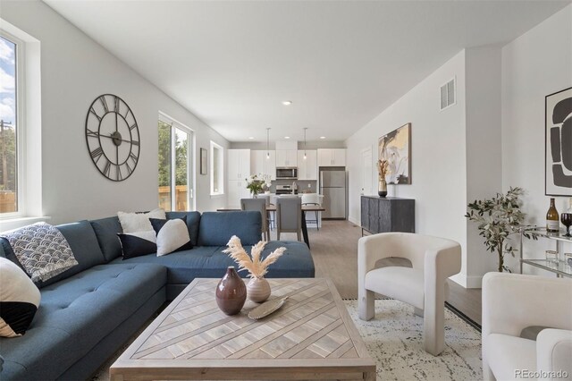 living area with visible vents, light wood-type flooring, and recessed lighting