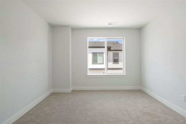 carpeted empty room featuring baseboards and visible vents