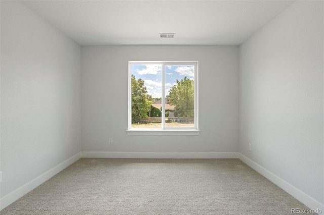 empty room featuring baseboards, visible vents, and light colored carpet