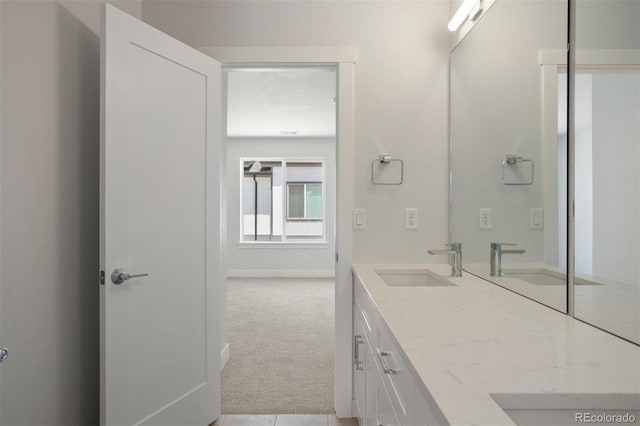 bathroom with double vanity, a sink, and baseboards