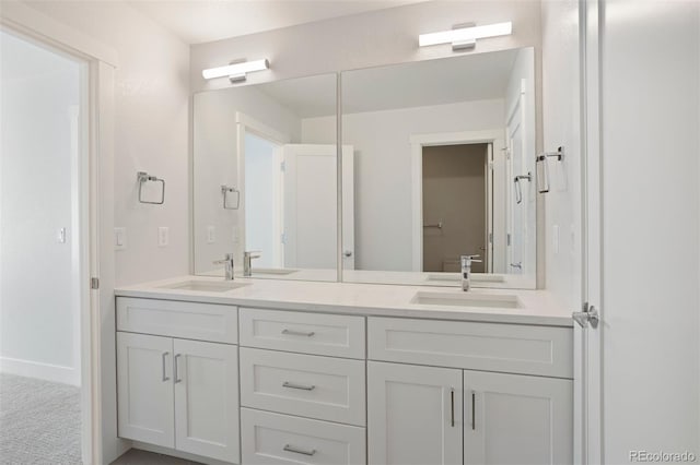 bathroom featuring double vanity, a sink, and baseboards