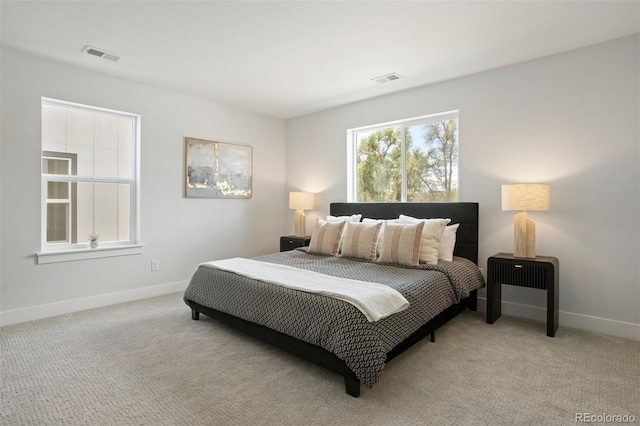 bedroom with baseboards, visible vents, and light colored carpet