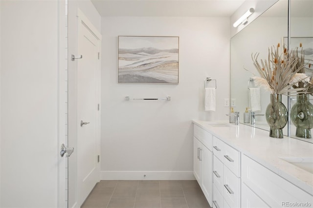 bathroom featuring double vanity, a sink, tile patterned floors, and baseboards