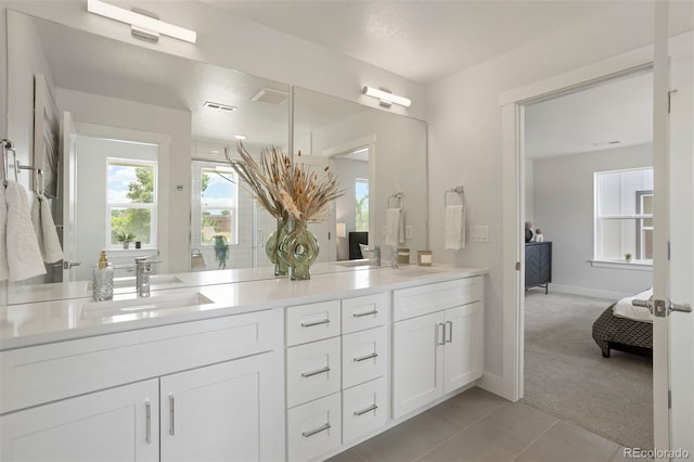 ensuite bathroom featuring baseboards, double vanity, connected bathroom, and a sink