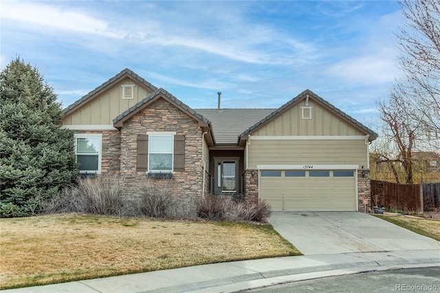 craftsman house with board and batten siding, a front yard, an attached garage, and stone siding