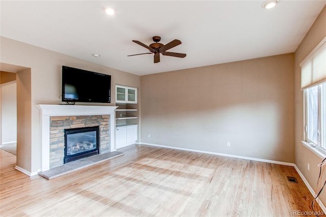 unfurnished living room featuring ceiling fan, baseboards, wood finished floors, and a fireplace