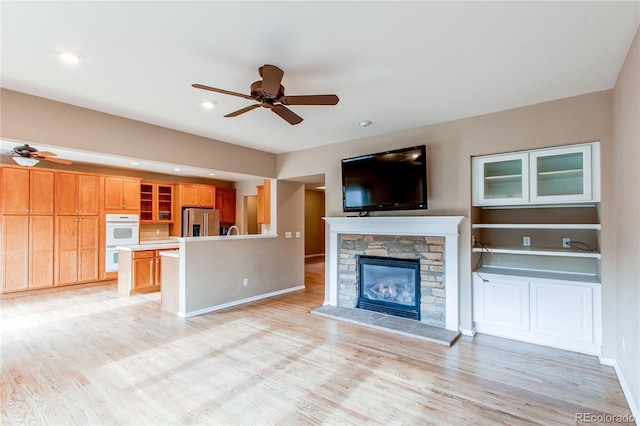 unfurnished living room featuring light wood-style floors, a fireplace, and a ceiling fan