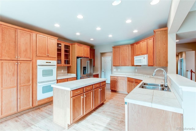 kitchen with a center island, a sink, white appliances, light wood finished floors, and recessed lighting
