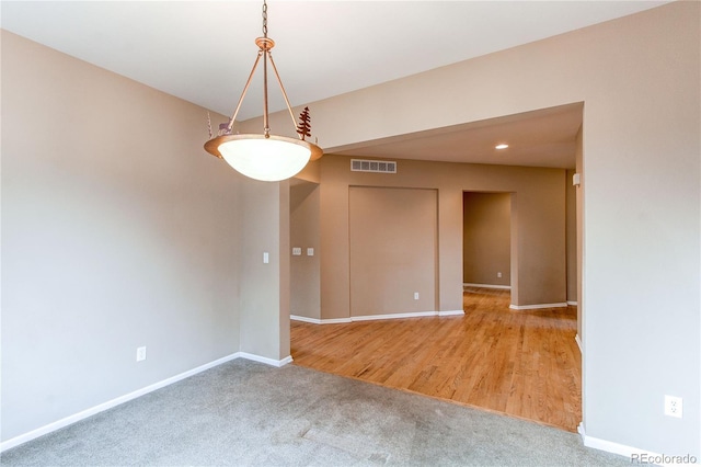 carpeted spare room featuring visible vents and baseboards