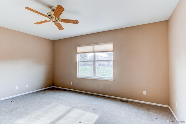 carpeted spare room with visible vents, baseboards, and ceiling fan
