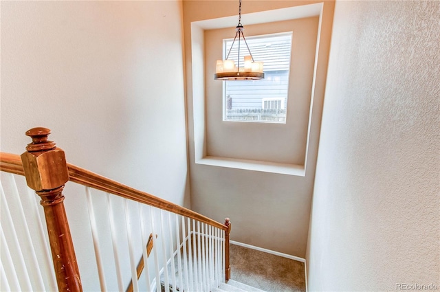 stairway featuring a notable chandelier, baseboards, and carpet floors
