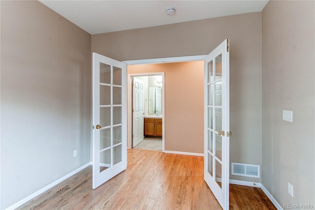 spare room with light wood-style floors, french doors, baseboards, and visible vents
