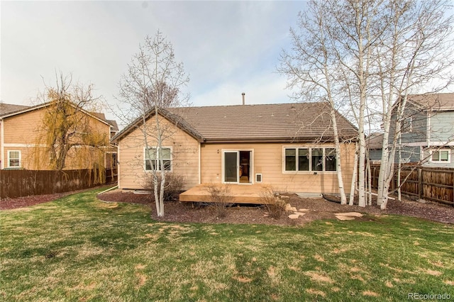 back of house featuring roof with shingles, fence, and a lawn