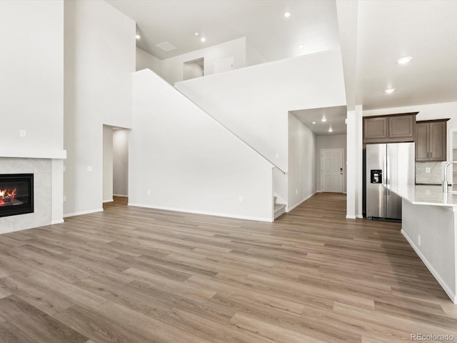 1612 Colorado River Dr, Windsor, CO 80550 - unfurnished living room with light wood-style floors, stairs, a towering ceiling, a fireplace, and recessed lighting
