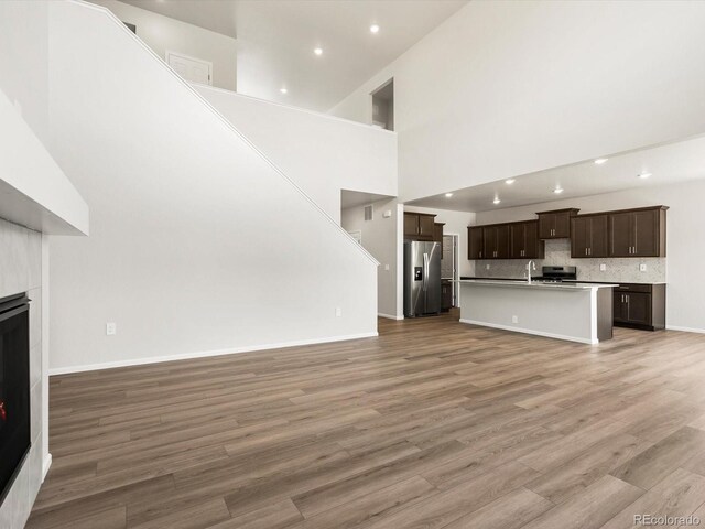 1612 Colorado River Dr, Windsor, CO 80550 - unfurnished living room featuring light wood-type flooring, a fireplace, recessed lighting, and a towering ceiling